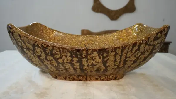 Golden Sail vessel sink with a curved boat-like silhouette, gold crystal interior, and dark textured artisan exterior by Majestics Group.