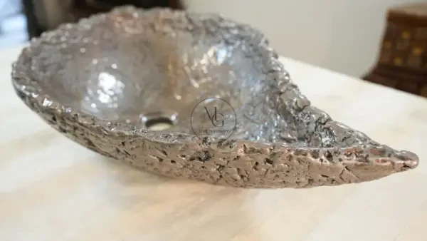 Elongated leaf-shaped artisan washbasin with textured silver leaf finish by Majestics Group.